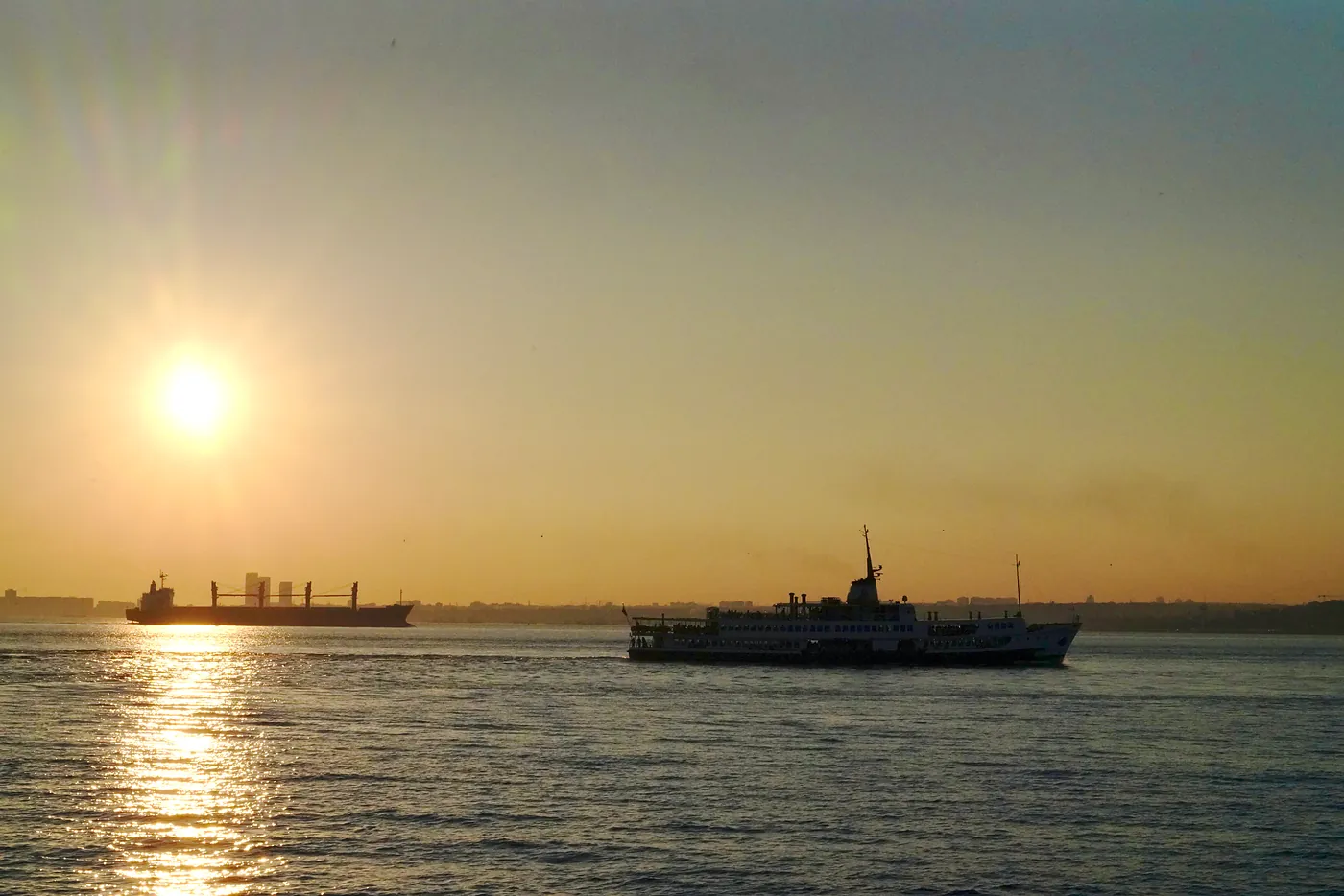 A ferry boat and a cargo ship sailing north.